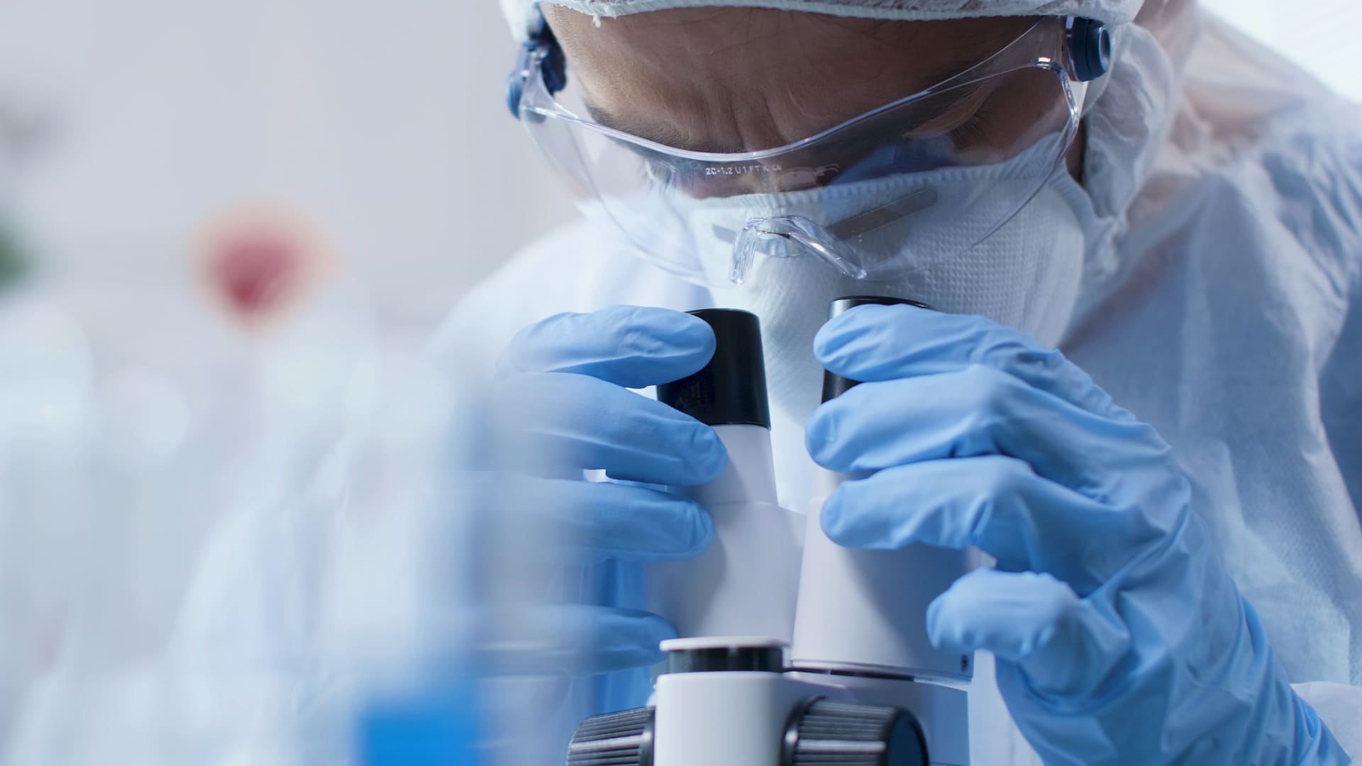 Closeup scientist doctor looking into medical microscope analyzing blood sample scientific experiment biochemistry laboratory researcher man developing vaccine against covid19 (2) (1) (1)